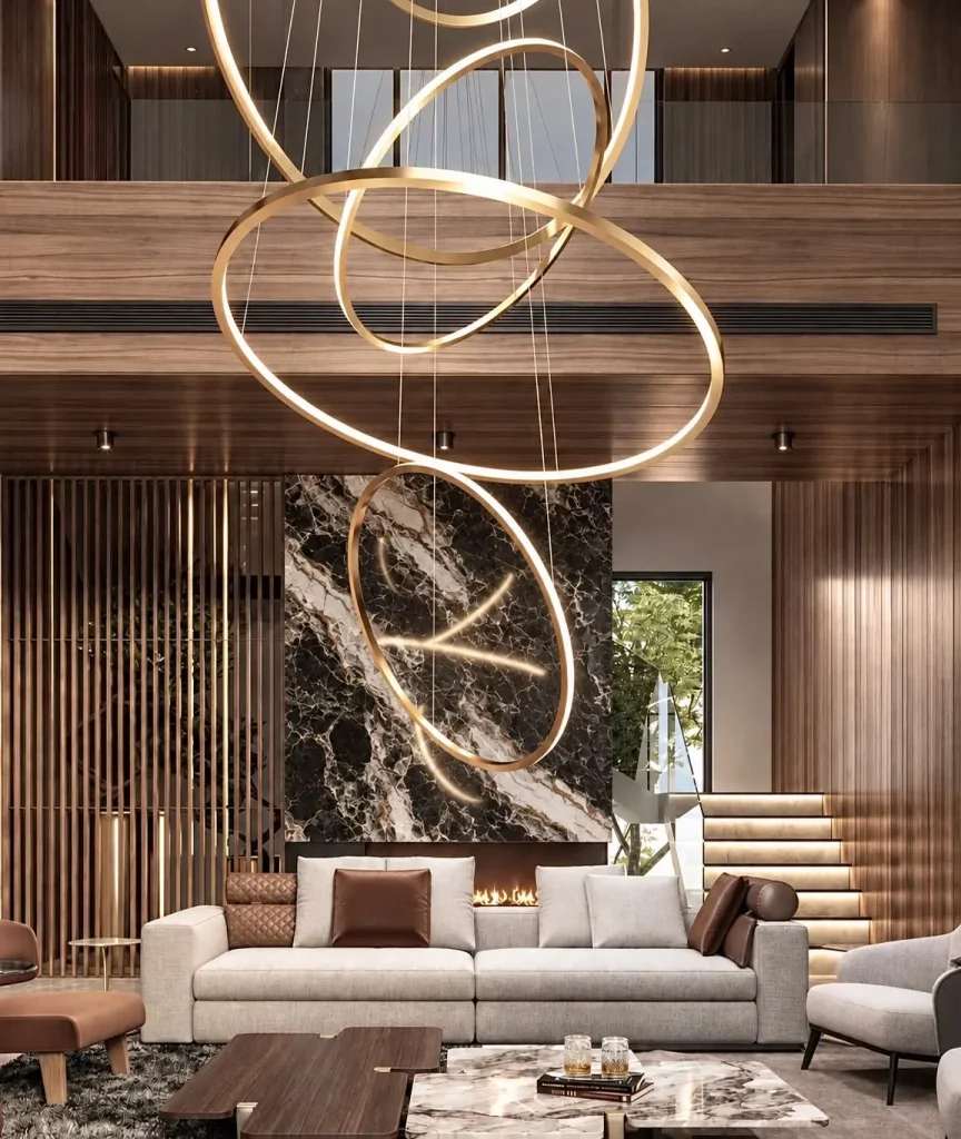 Sala de estar com lustre de anéis dourados, painel em mármore e pé-direito duplo — projeto residencial Linguagem dos interiores, Michelle Rigopoulos